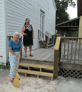 JoRita Stevens, Director and Recording Secretary, sweeps sand into the new brick entry to our campus, overseen by our Site Manager Linda Garcia.