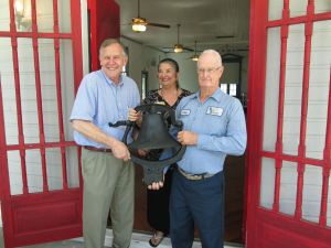Jon Moore and Linda Garcia accepting an antique steeple bell from Jack Helm of Helm Vault